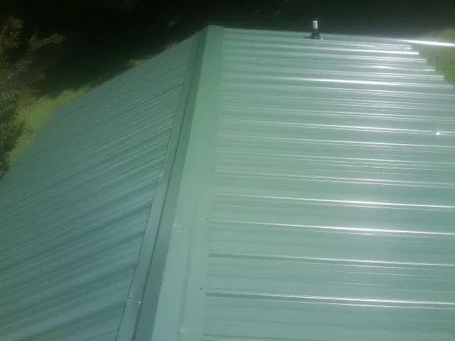 New green metal panels meeting at the ridge of a roof — Flat Roof Repair work by our crew in Seneca